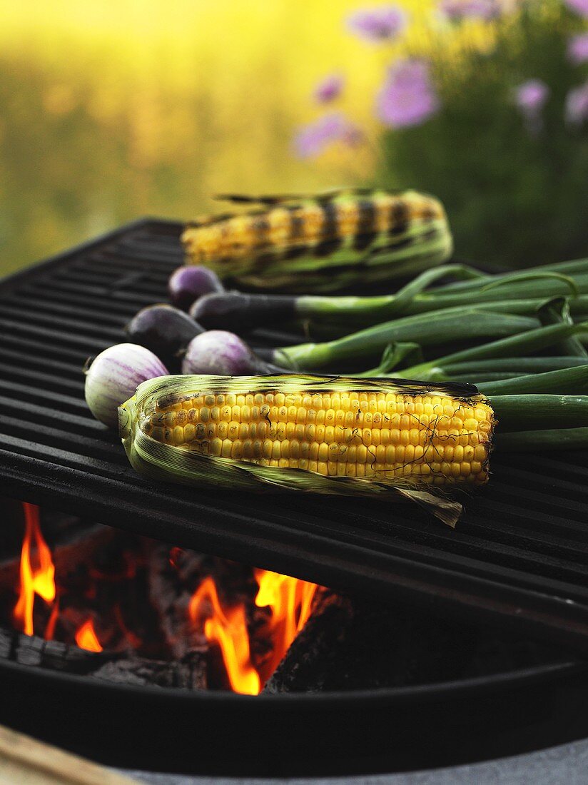 Corn on the cob and spring onions on a barbecue