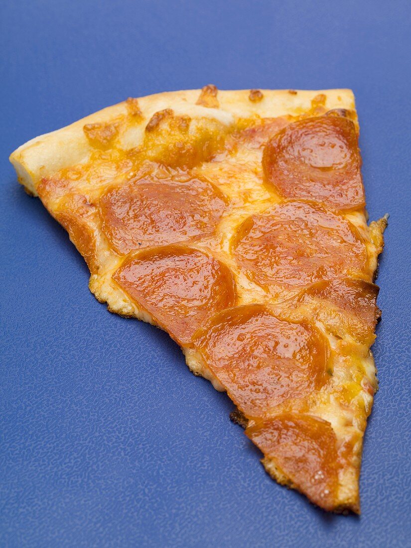 A slice of salami pizza on blue background