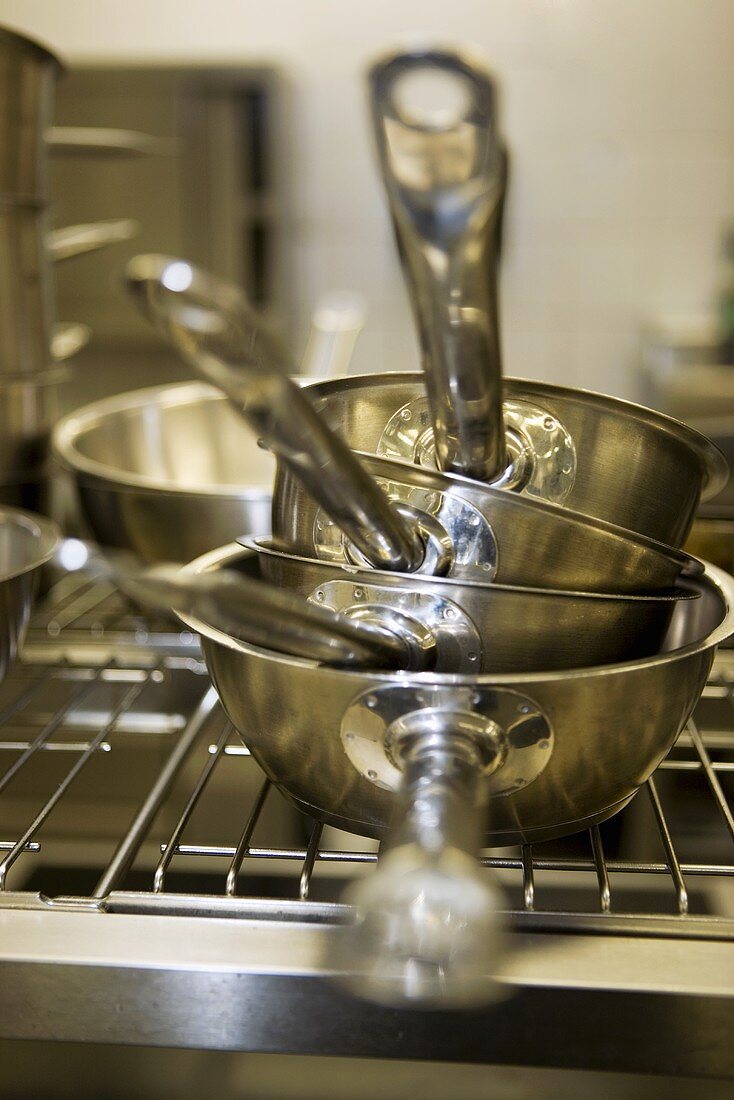 Four stacked sauté pans in a restaurant kitchen