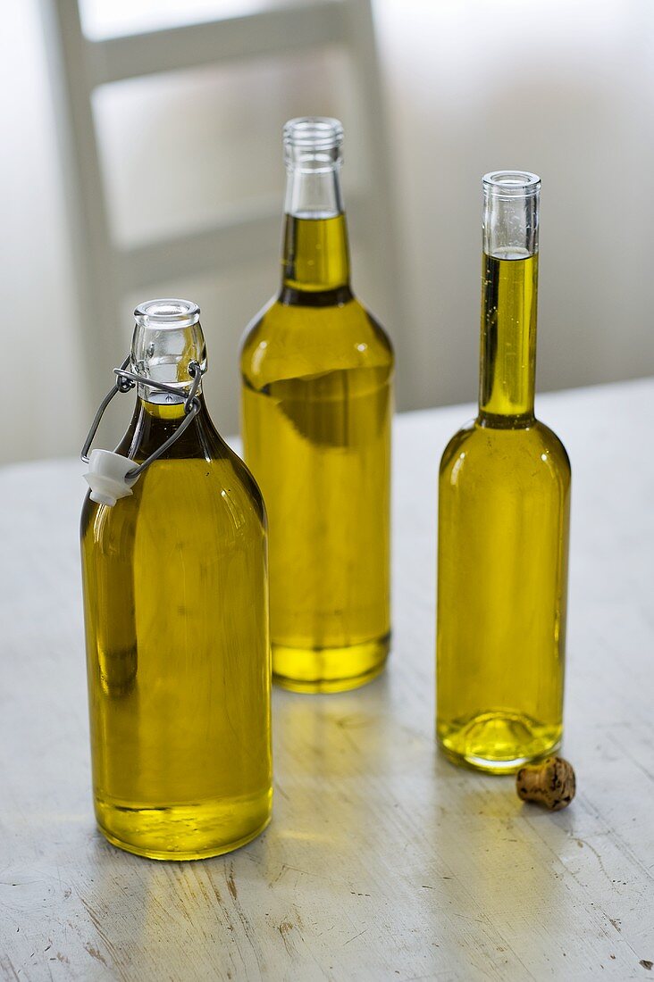 Drei Flaschen Olivenöl auf Holztisch