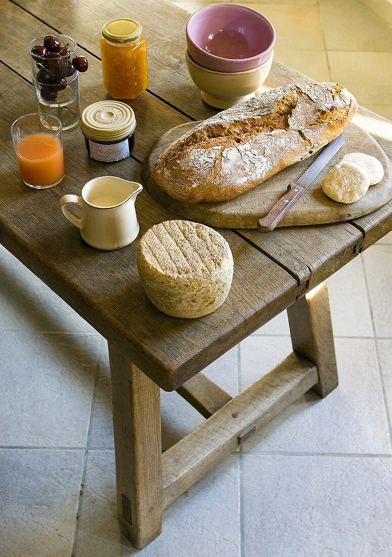 Käse, Brot, Milch, Marmelade auf rustikalem Holztisch