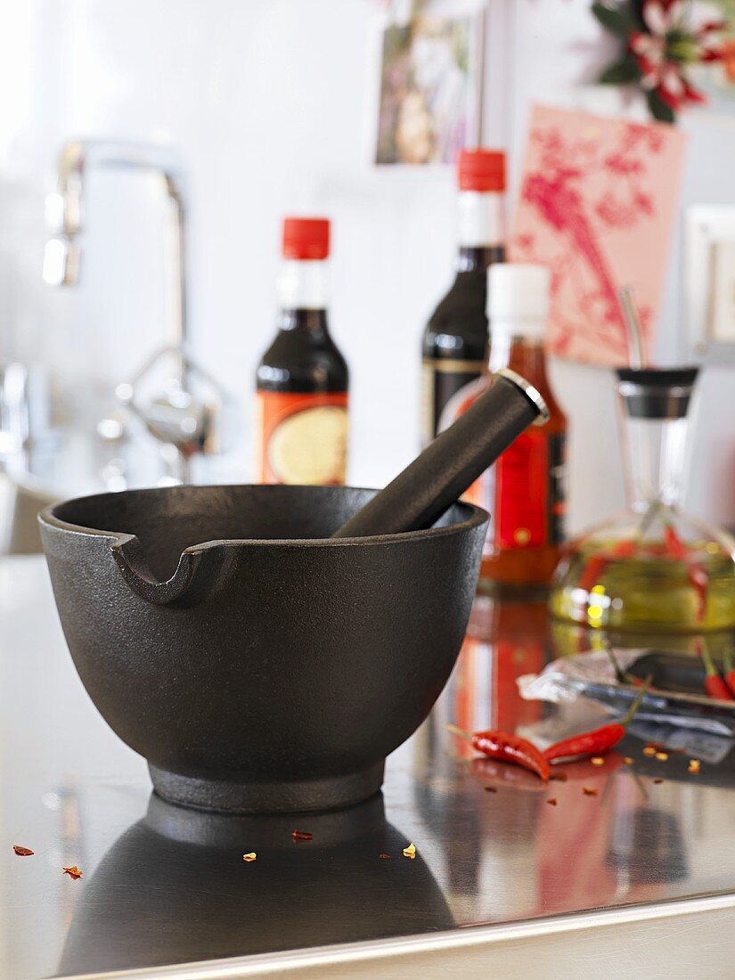 Pestle and mortar, spicy sauces and chillies in kitchen