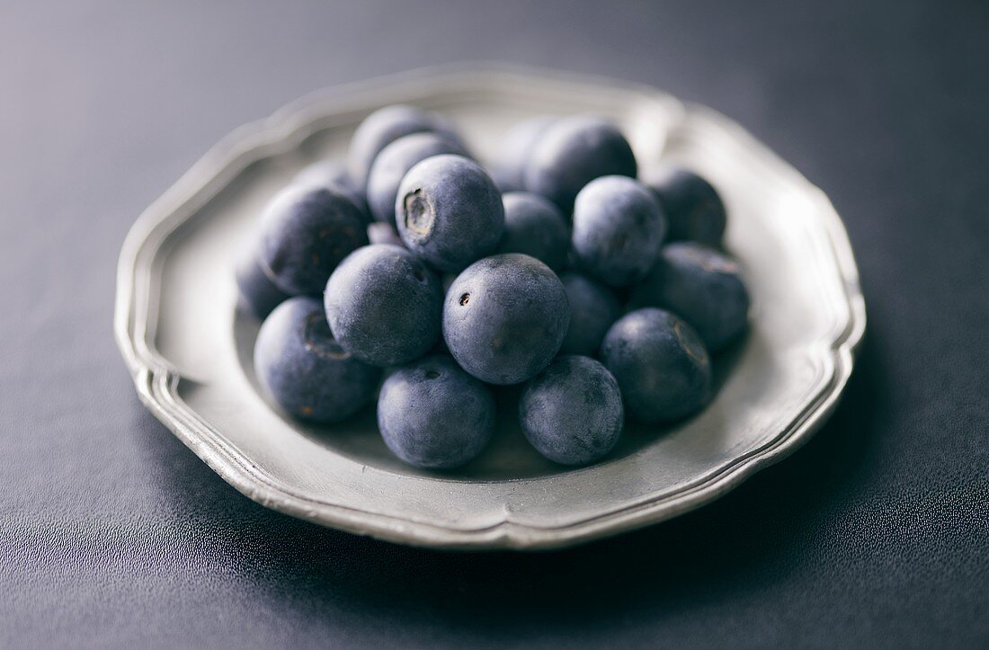 Several blueberries on pewter plate