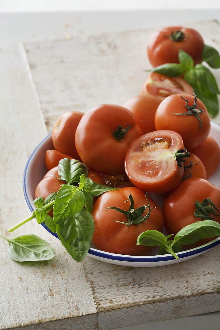 Ganze und halbe Tomaten und Basilikum