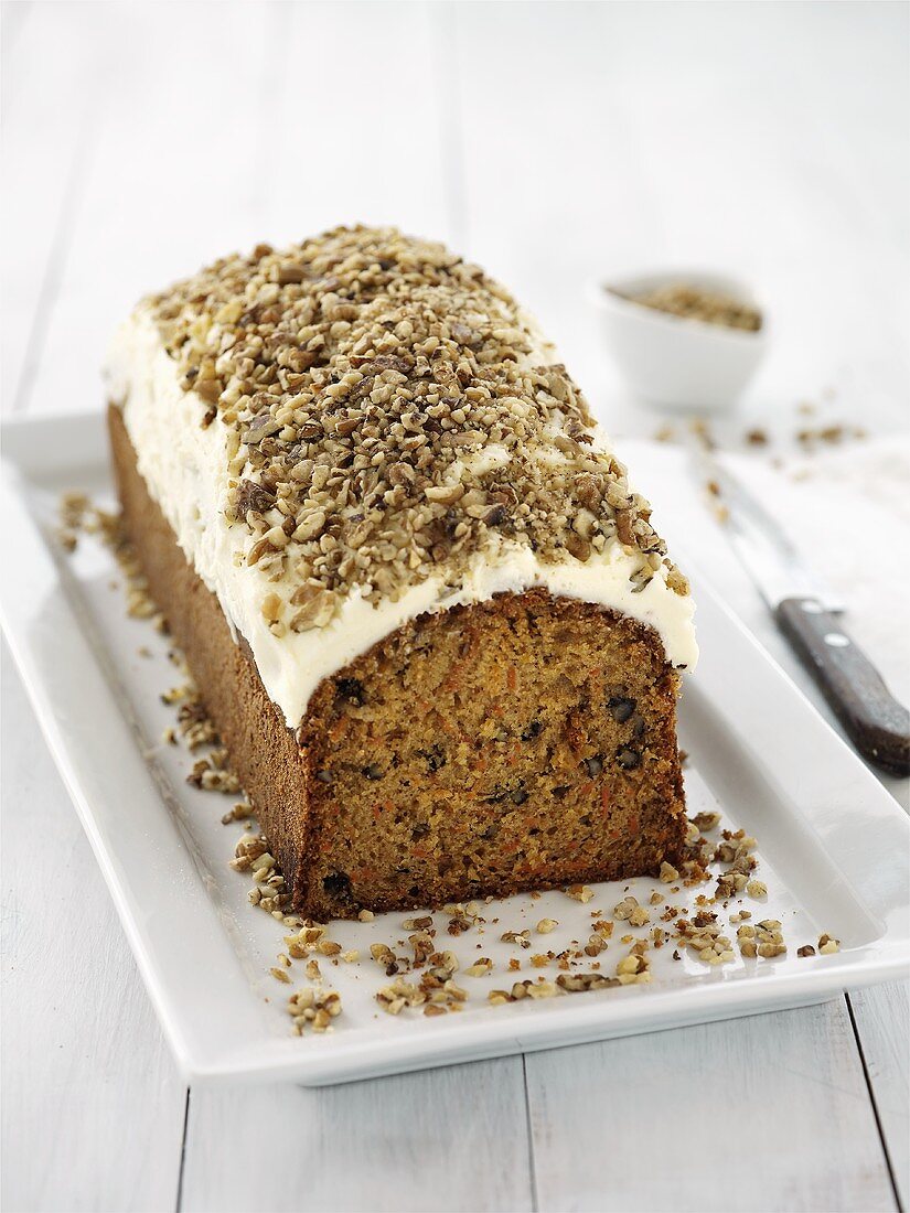 Carrot cake with cream topping and chopped nuts