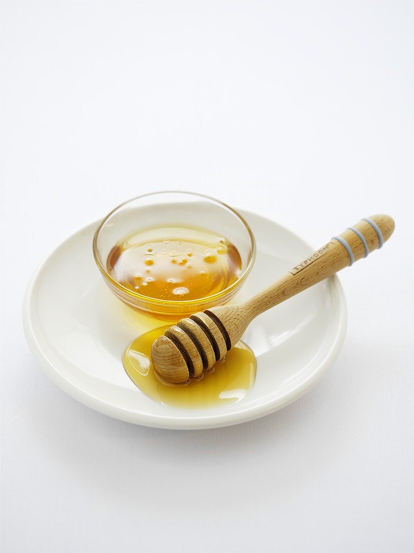 Honig im Schälchen und auf Honiglöffel