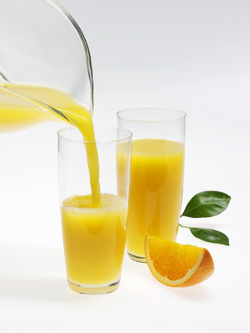 Orangensaft in Glas einschenken