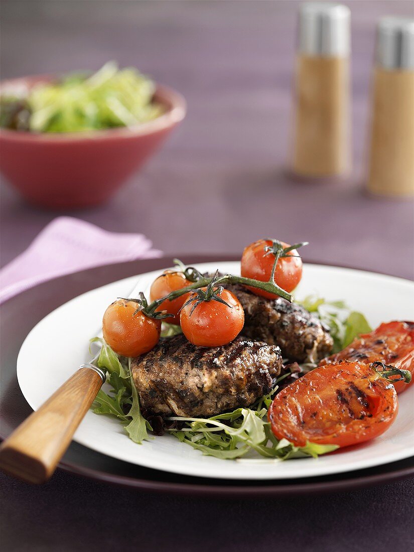 Gegrillte Hamburger auf Rucola mit gegrillten Tomaten