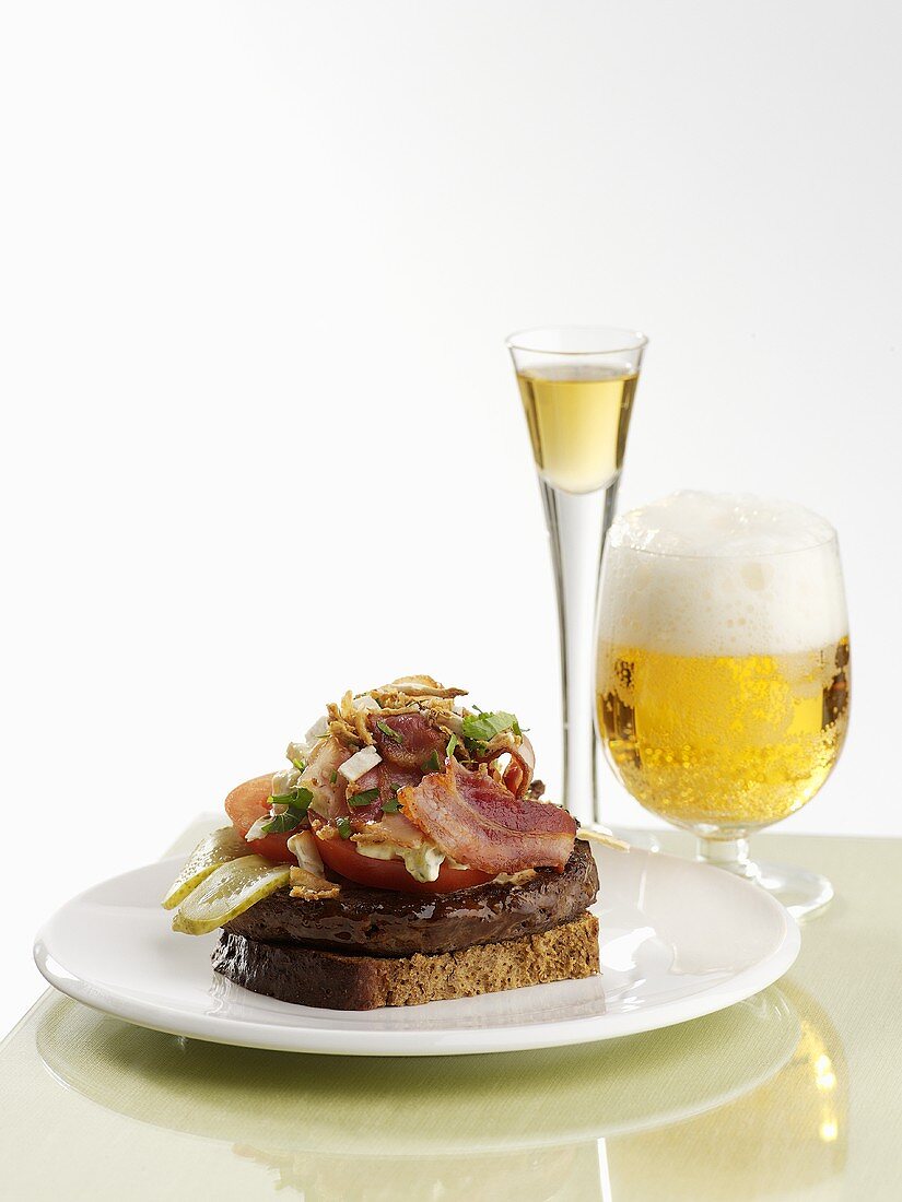 Burger, tomato and bacon on bread, glass of beer