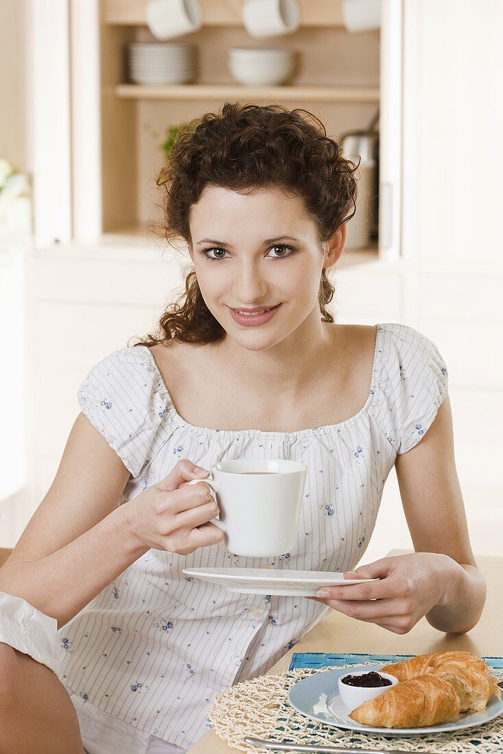 Junge Frau trinkt Kaffee am Frühstückstisch