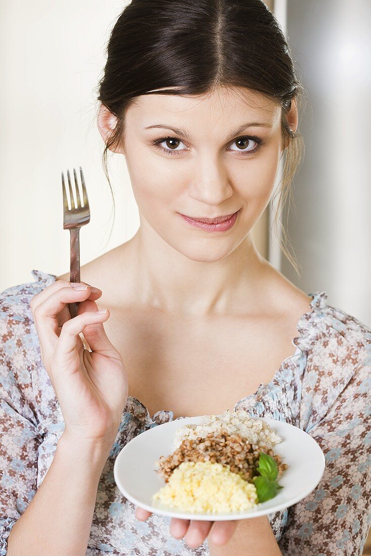 Young woman holding a plate of cooked grains