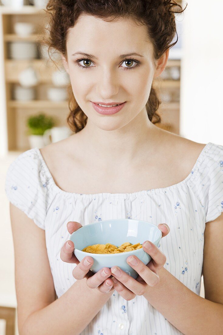 Junge Frau hält eine Schale mit Cornflakes