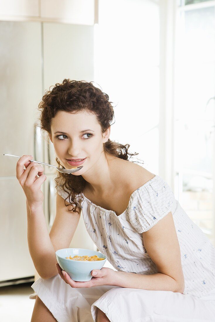 Young woman eating cornflakes with milk