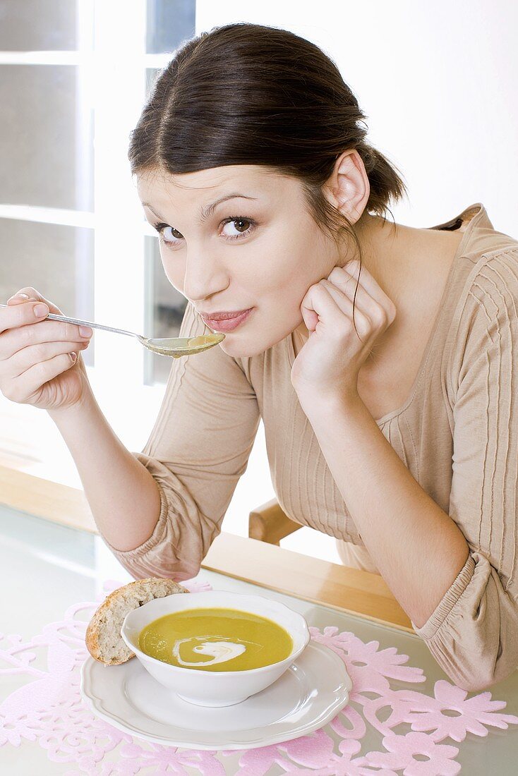 Young woman eating cream of pea soup