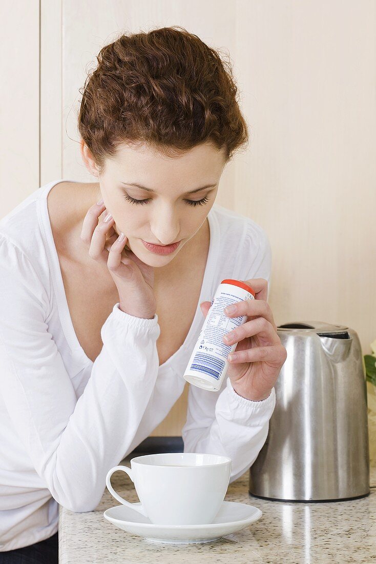 Young woman putting sweeteners into a cup of coffee