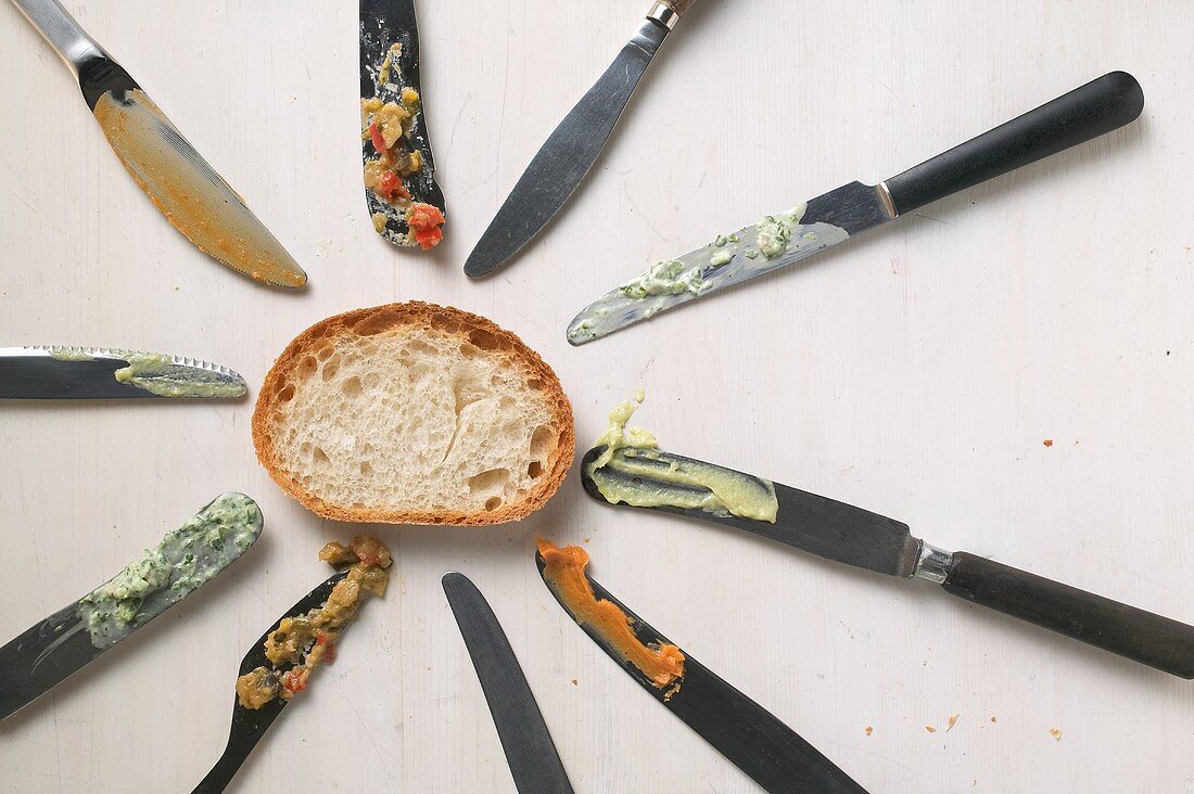 Knives with the remains of spreads and a slice of bread