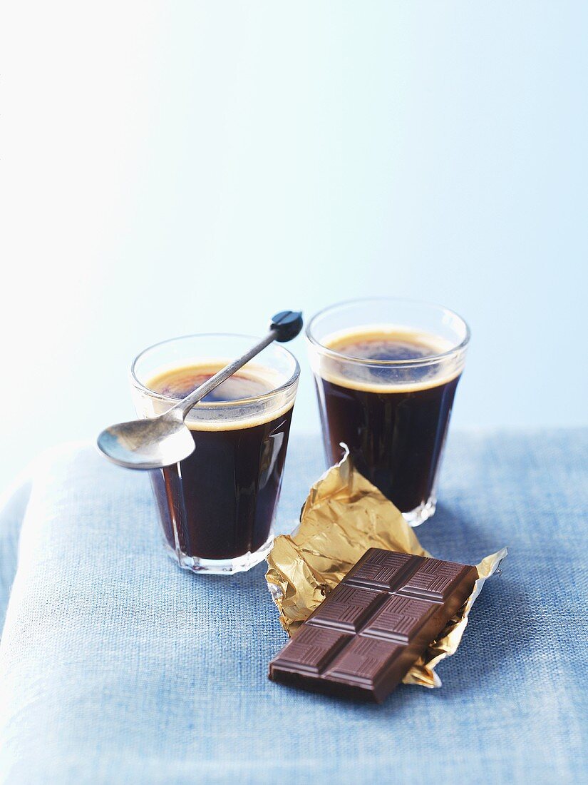 Schwarzer Kaffee in zwei Gläsern und Schokolade