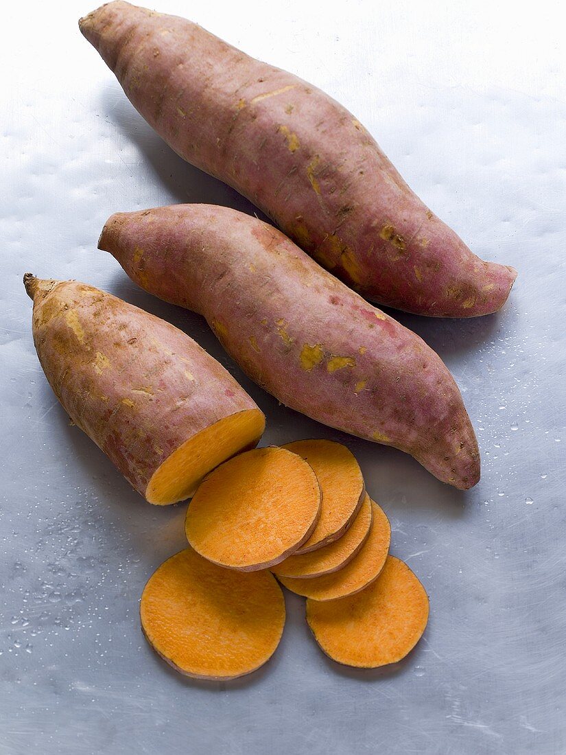 Three sweet potatoes, one partly sliced