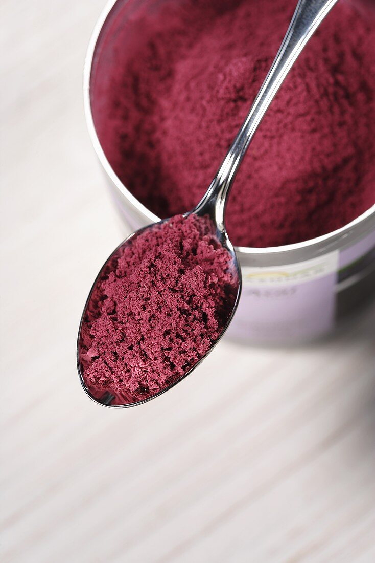 Acai powder (diet aid) on spoon and in tin