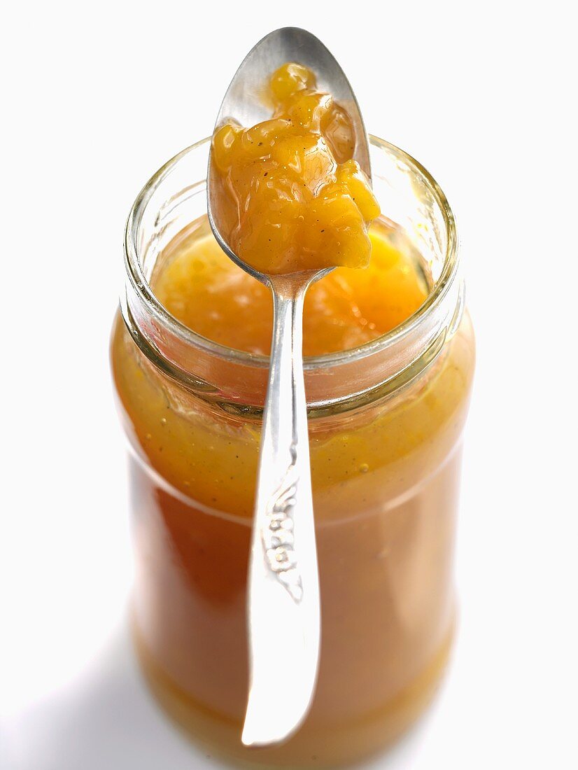 Peach and mango jam in jar with spoon