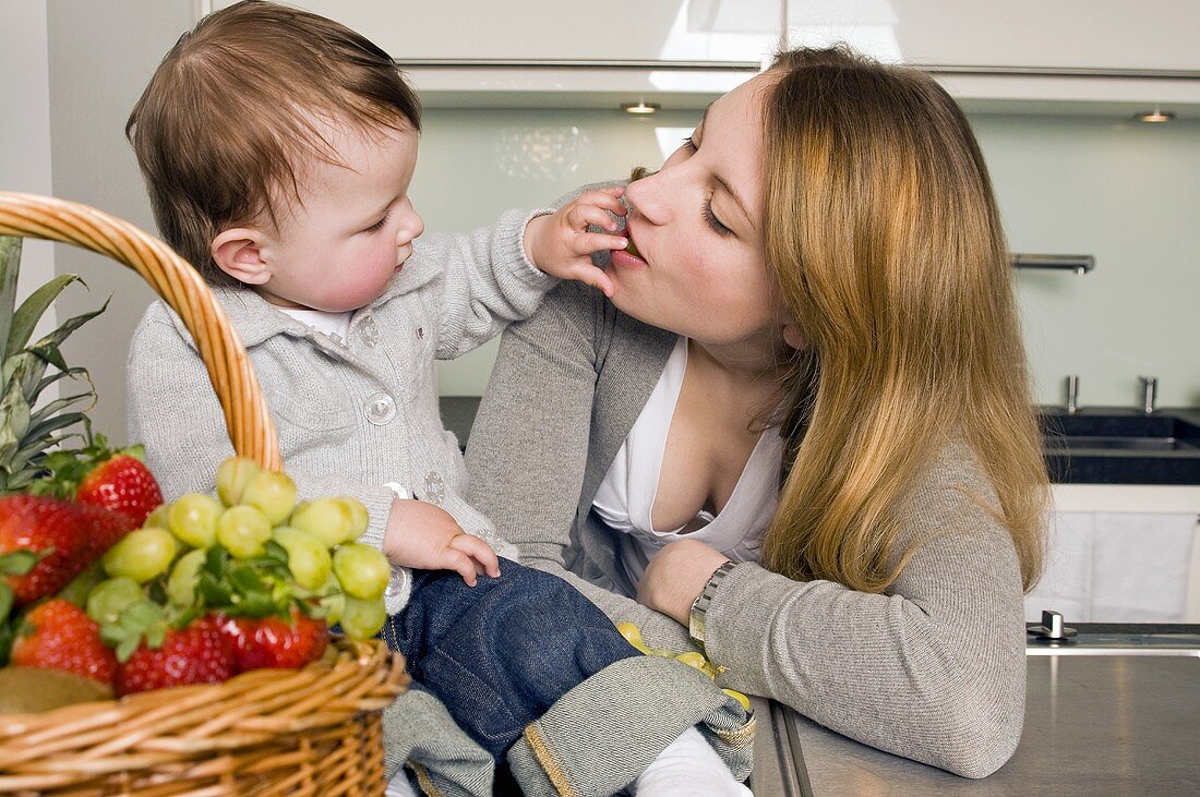 Toddler with mother beside a basket of fruit