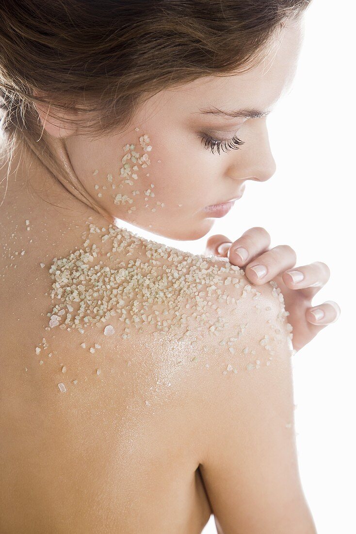 Young woman with exfoliating scrub on her shoulder
