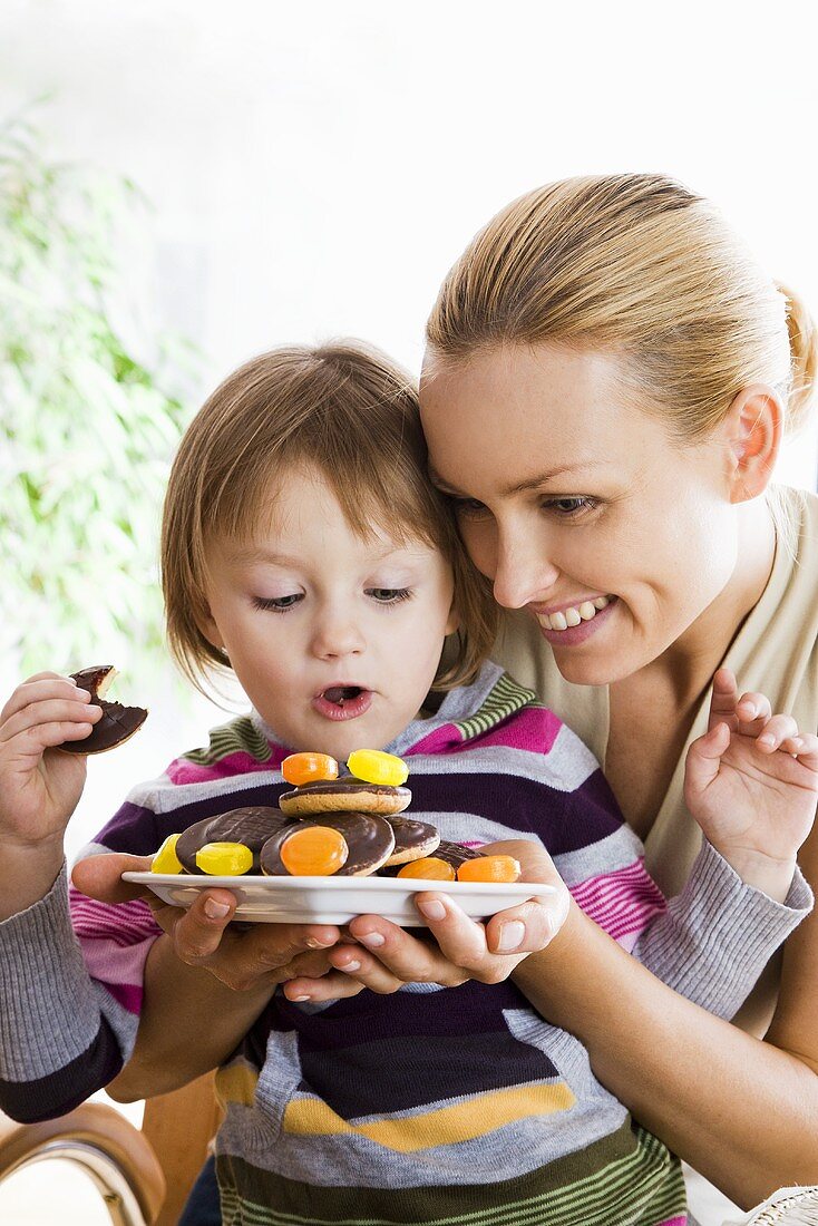 Little girl with mother eating a biscuit