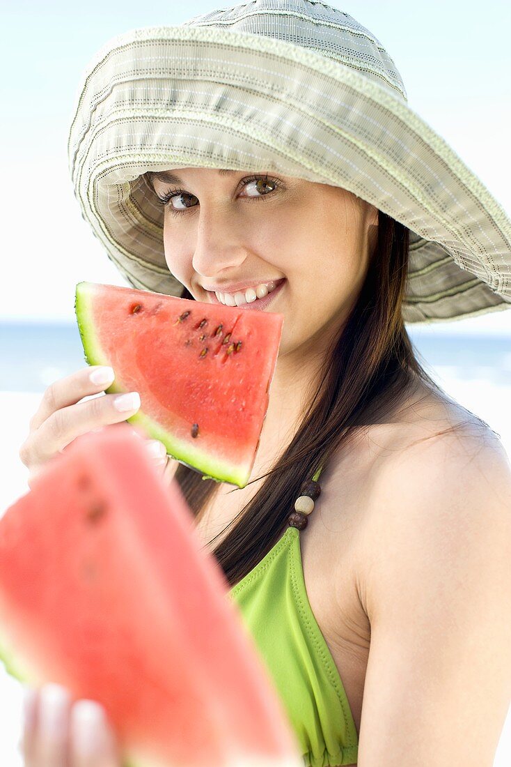 Junge Frau isst Wassermelone am Strand