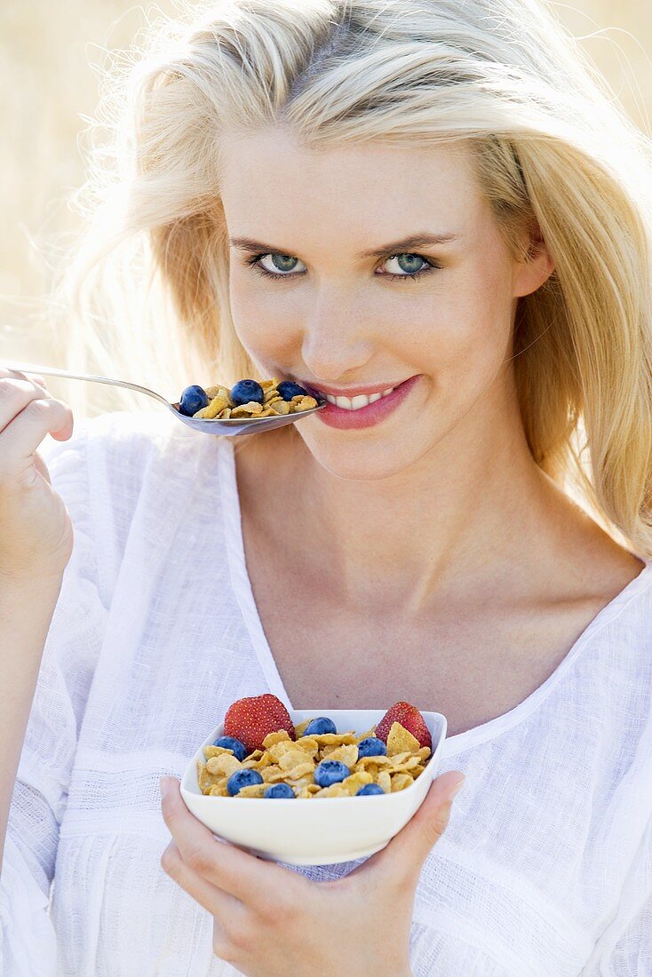 Blond woman with cornflakes and berries out of doors