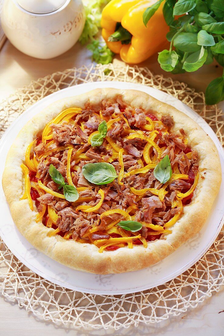 A round pizza topped with tuna, peppers and basil