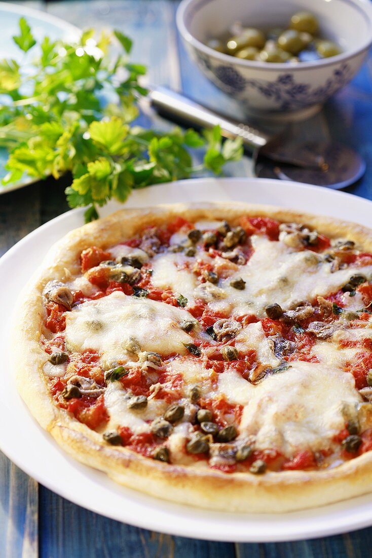 Pizza topped with tomatoes, anchovies, capers and cheese