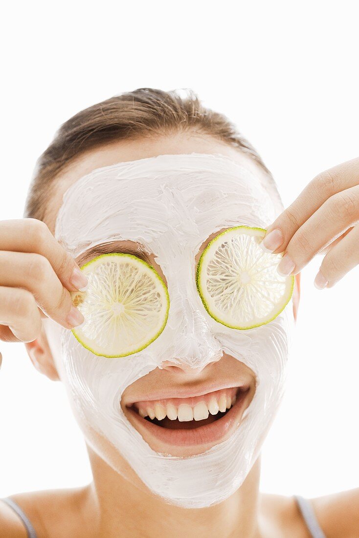 Woman with facial mask and slices of lime over her eyes