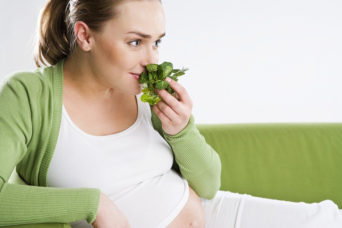 Pregnant woman smelling fresh salad leaves