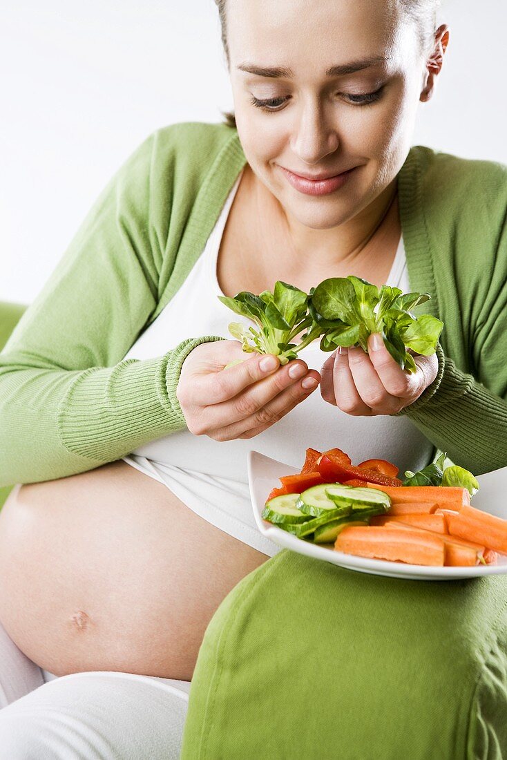 Schwangere Frau isst frisches Gemüse