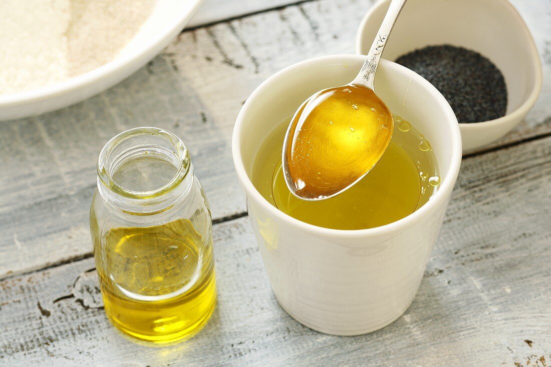 Spooning olive oil into a beaker of water