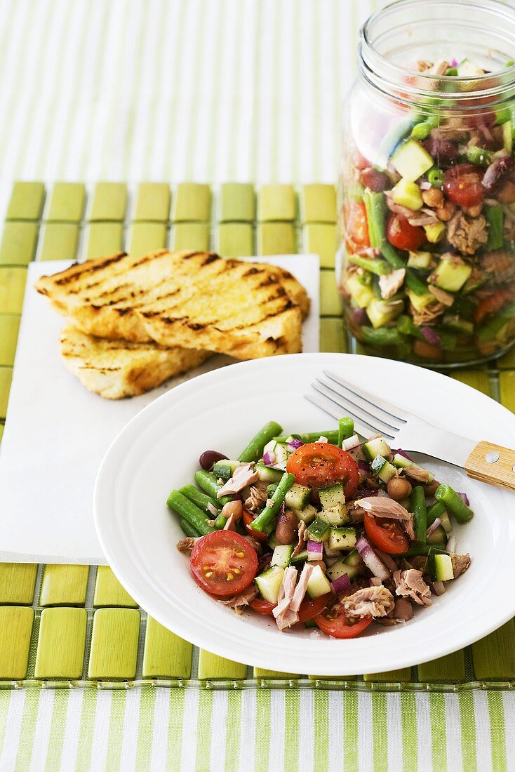 Bean, onion, cucumber and tomato salad in jar and on plate