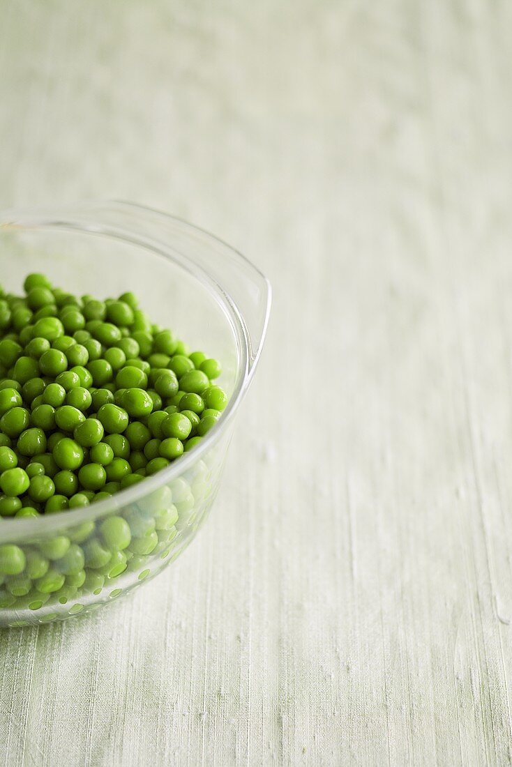 Cooked frozen peas in a glass bowl