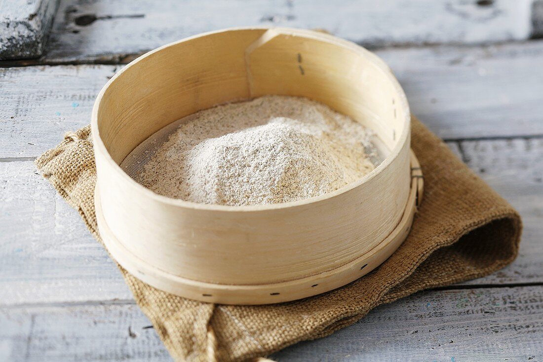 Wholemeal flour in a sieve on jute sack