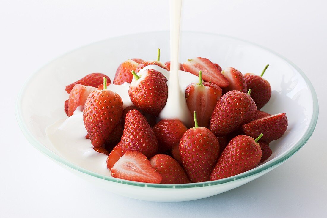 Pouring yoghurt over fresh strawberries