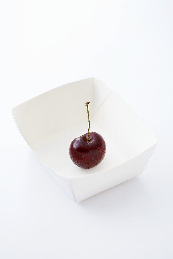 A cherry in a paper dish