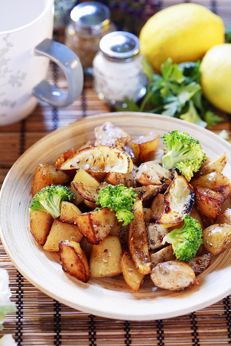 Roast potatoes with onions, broccoli and lemon wedges