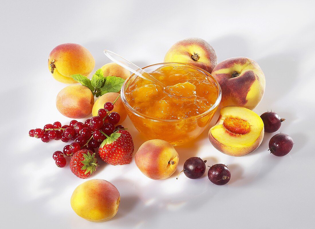 Aprikosenmarmelade, umgeben von frischem Obst