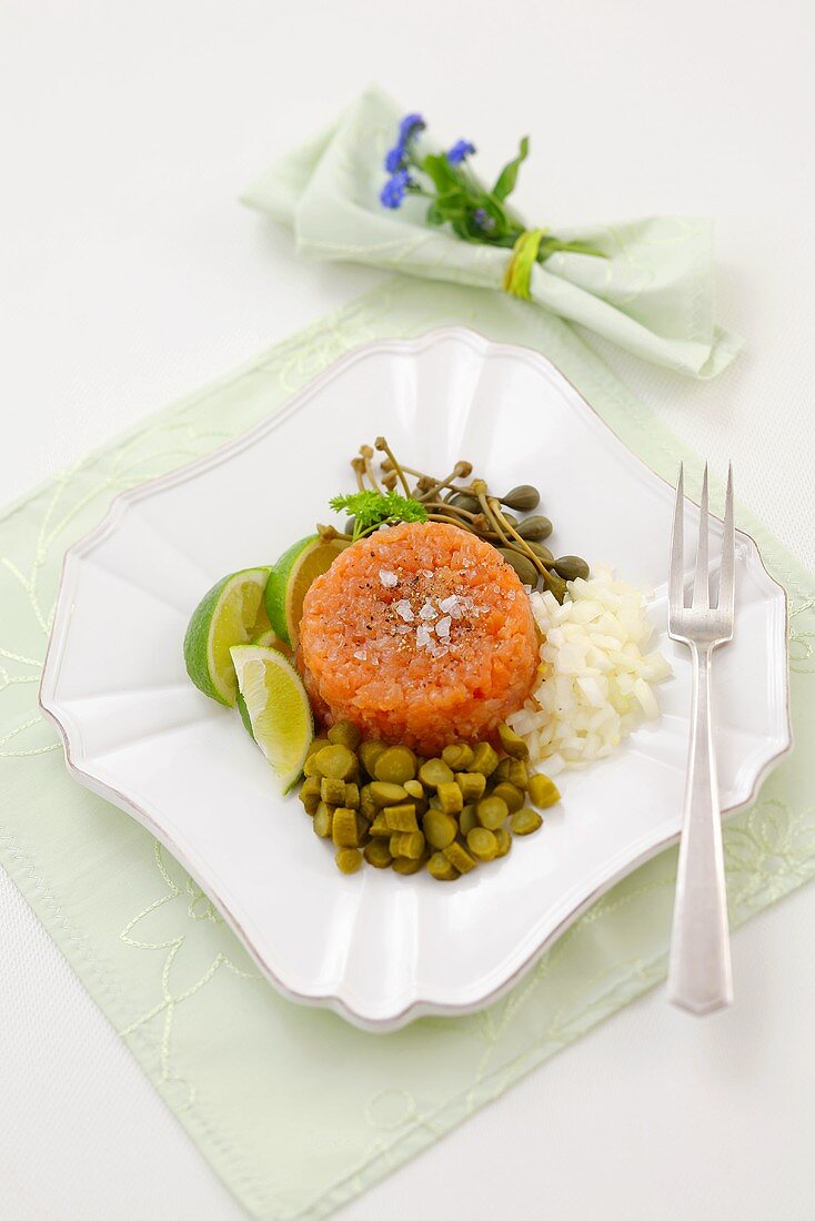 Salmon tartare with onions, gherkins, capers, lime wedges