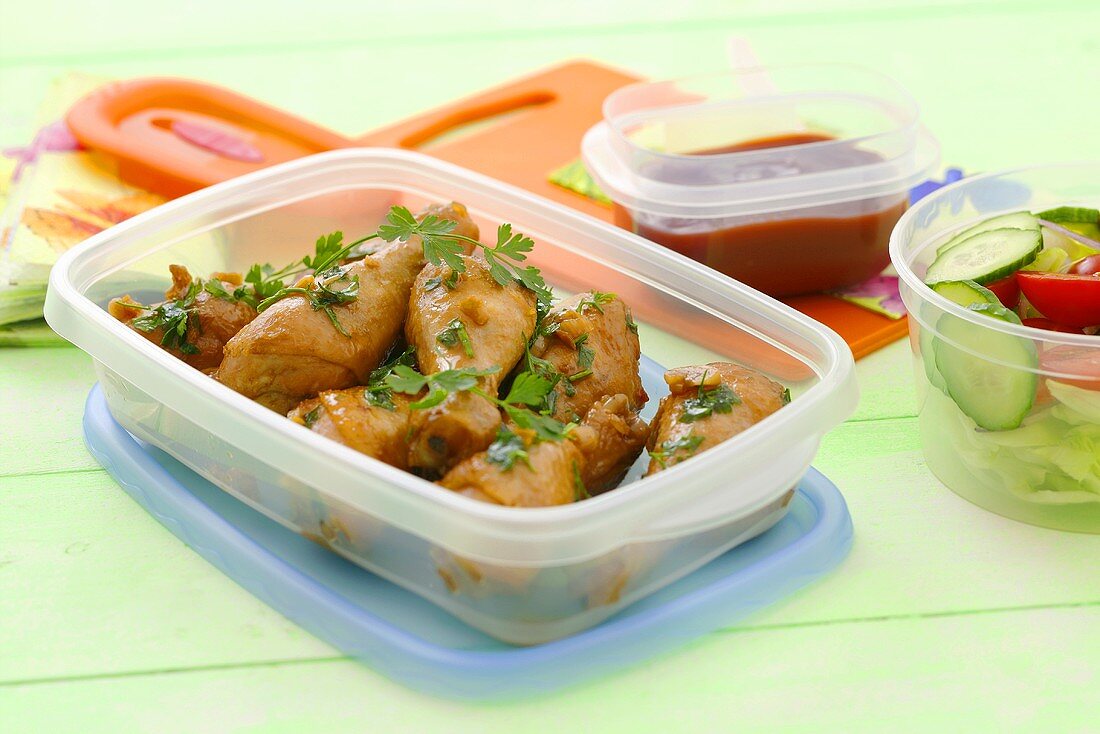 Chicken legs with parsley in a plastic box