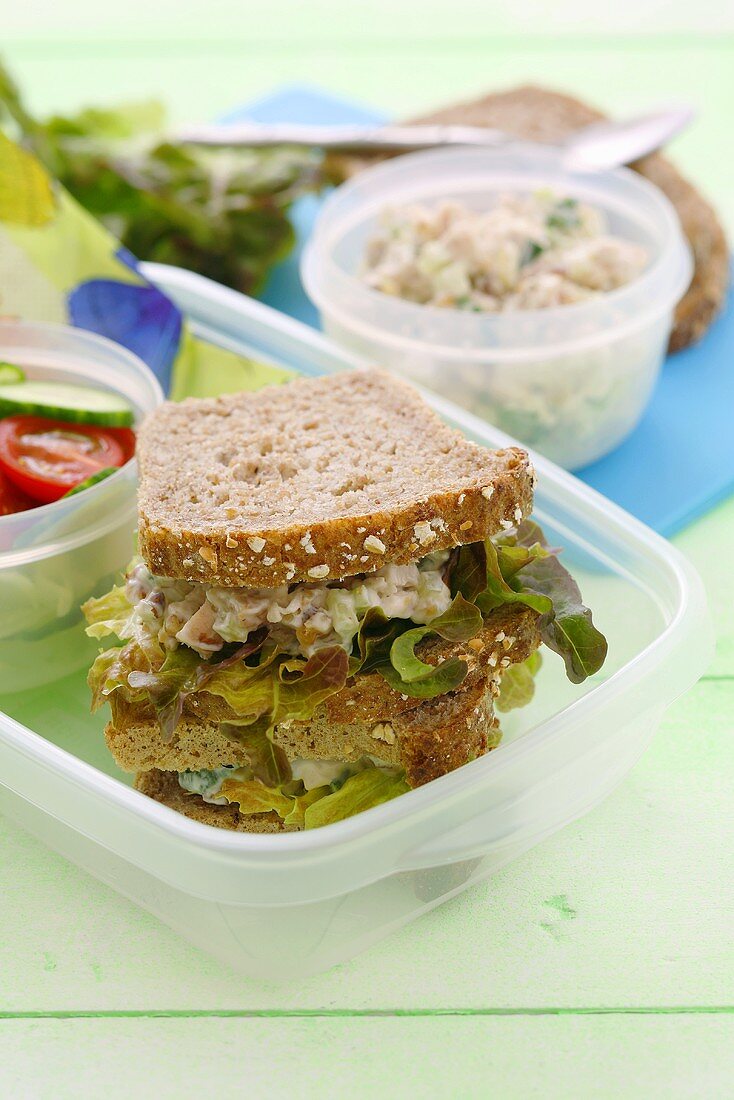 Sandwich mit Geflügelsalat und Blattsalat in Plastikbox