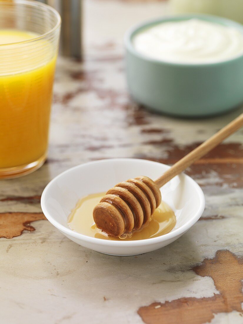 Honey dipper in a dish, yoghurt, orange juice