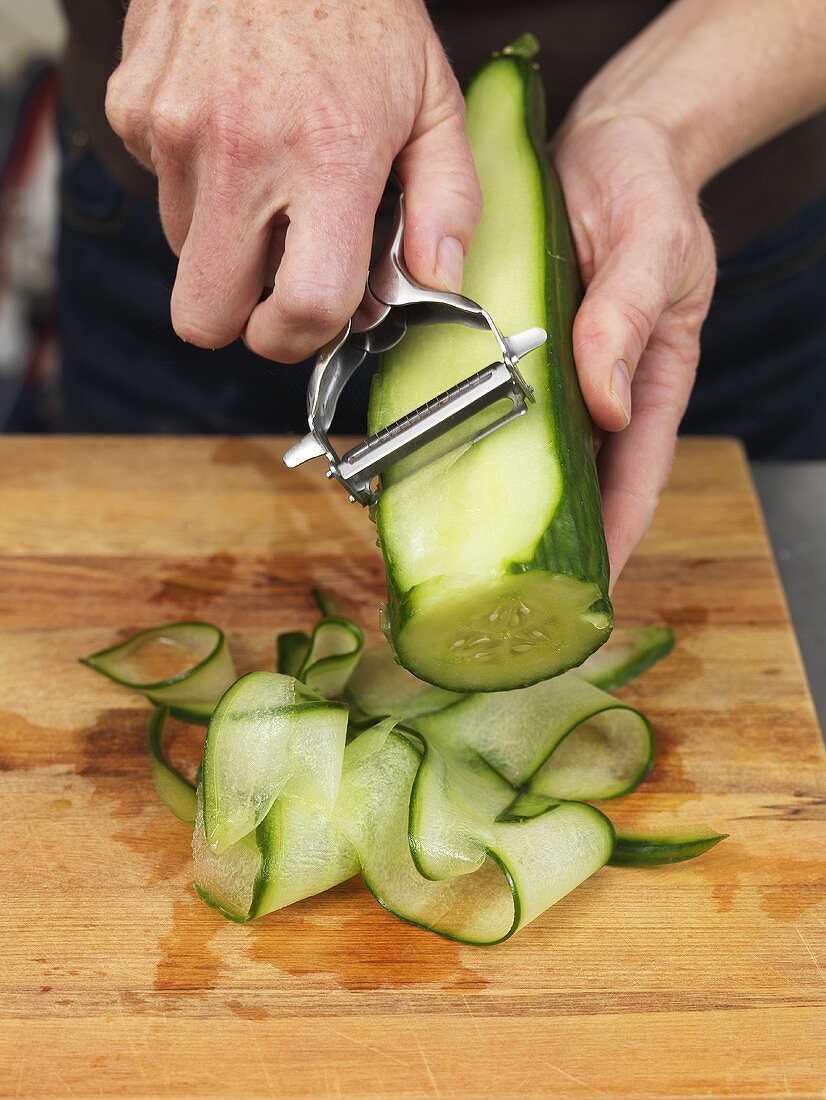 Man making cucumber ribbons with a vegetable peeler
