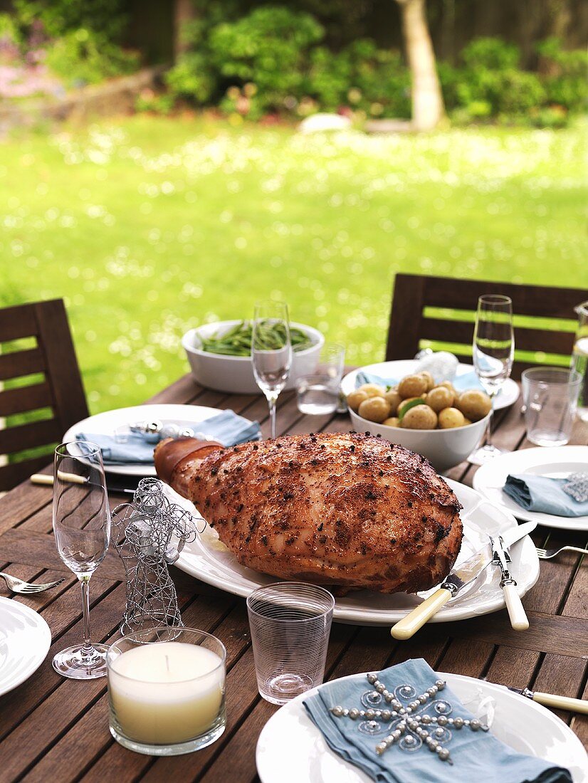 Orange and honey-glazed roast ham on table out of doors