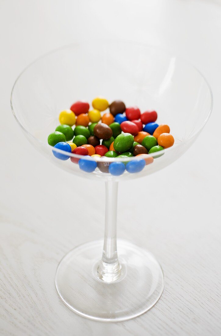 Different coloured chocolate-coated peanuts in a glass