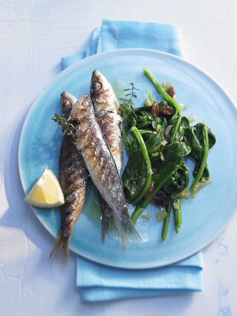 Sardines cooked in grill frying pan with spinach and lemon